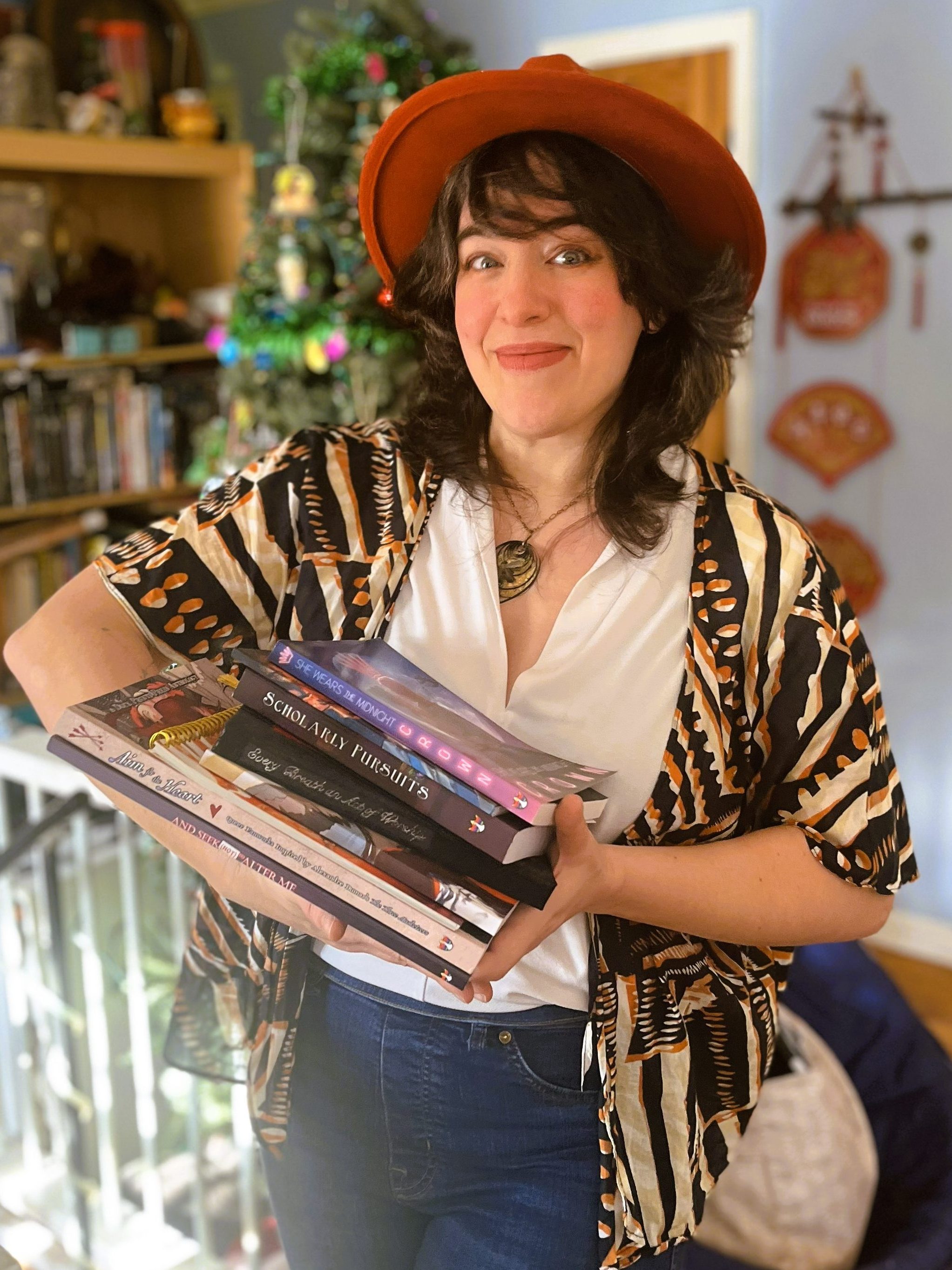 Lucy proudly smiling while cradling a stack of books, all of which contain some of her work.