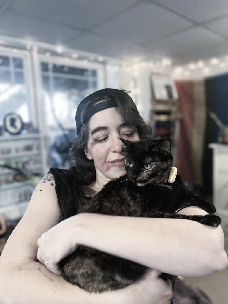 Photo of Lucy in fake battle-damaged makeup holding a tortoiseshell cat.